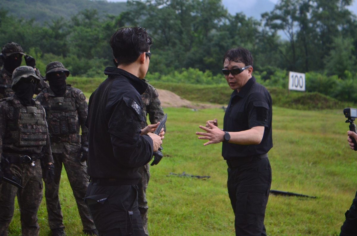 KKM instructor briefing armed special forces trainees in the field